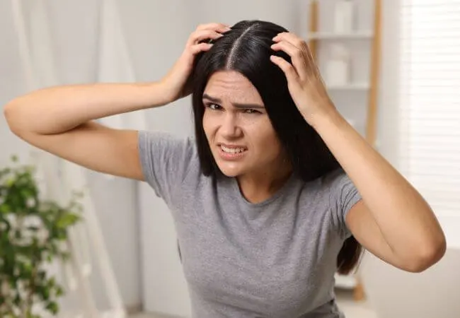 A woman examining flaking on her scalp.